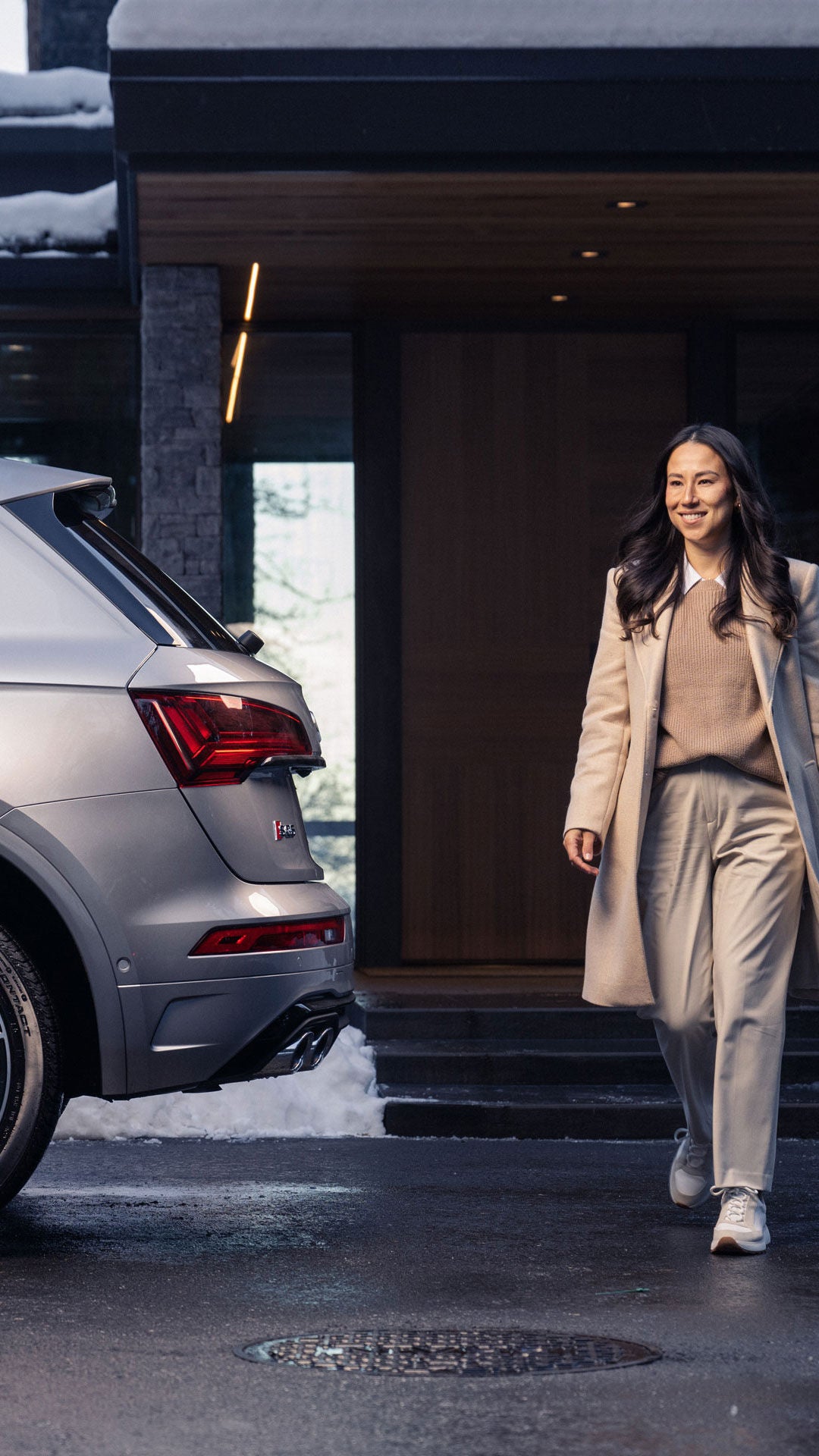 A woman standing next to a parked Audi SQ5.