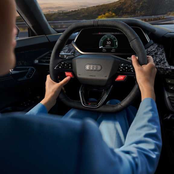 Interior view of a person driving the Audi RS e-tron GT driving on a road. 