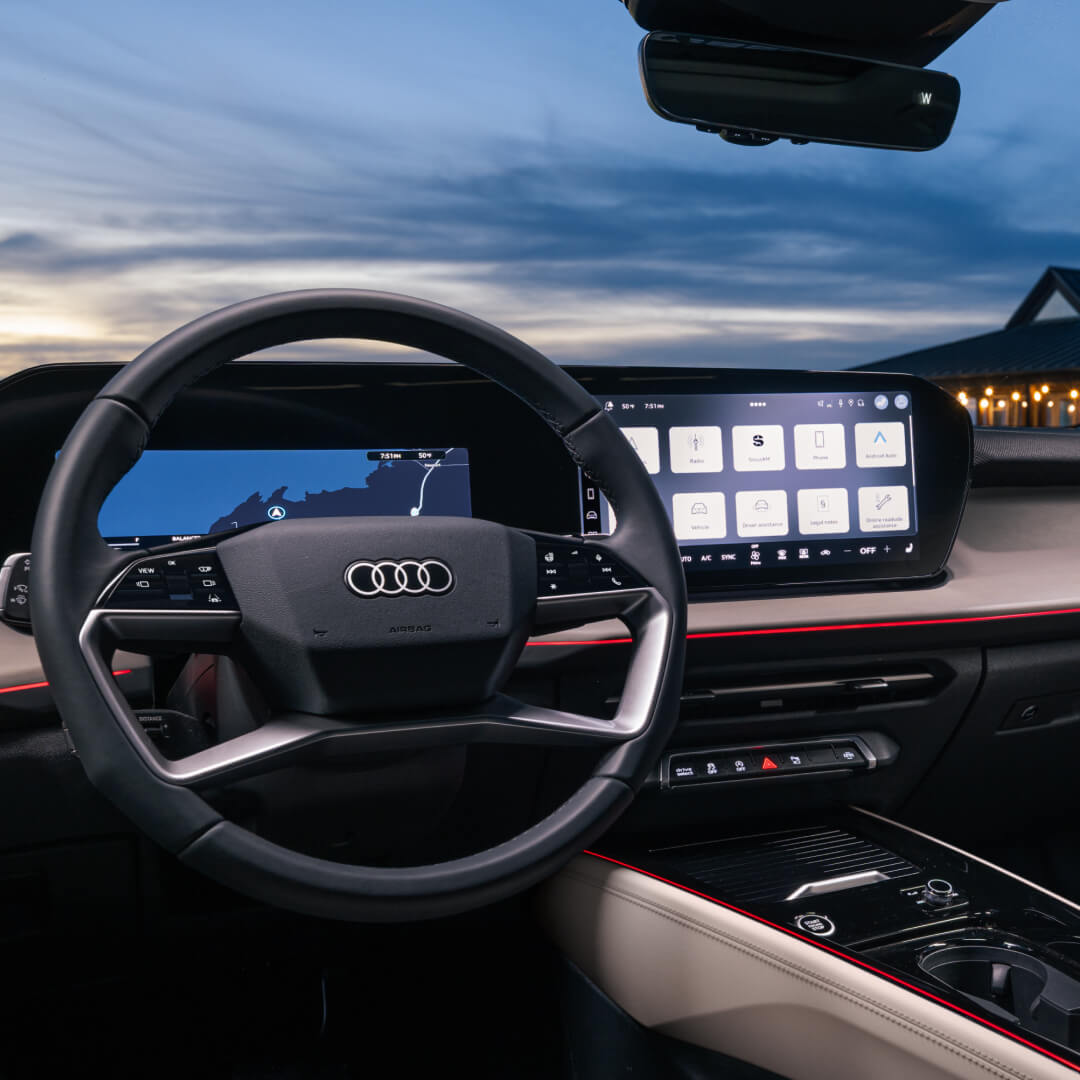 Interior close-up detail shot of an 2027 Audi Q3 steering wheel, center console and navigation infotainment screen.