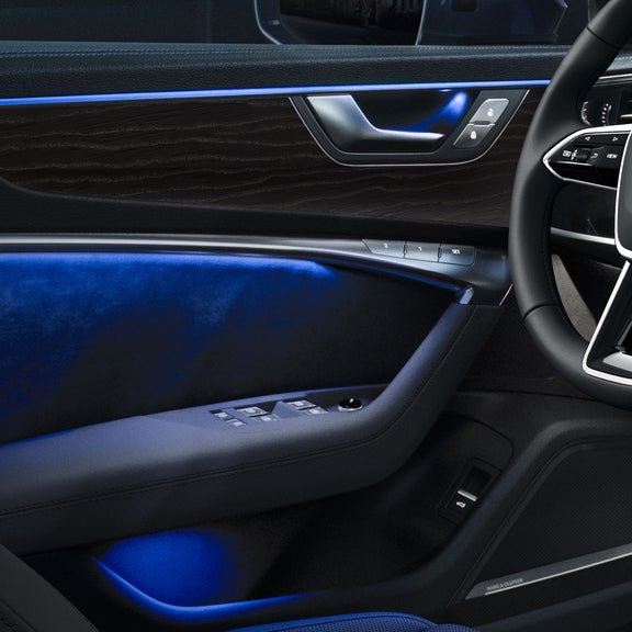 Close-up of the dashboard and console of the Audi A6 allroad® with blue interior lighting.