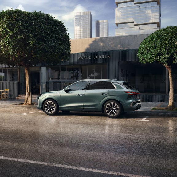 Vue latérale de l'Audi Q3 garée dans une rue de la ville près de la devanture d'un magasin.