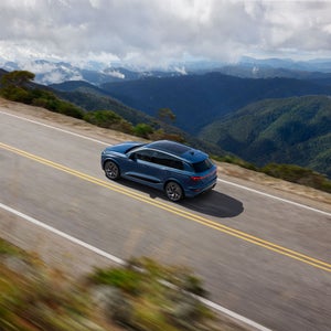 Aerial side view of the Audi SQ6 e-tron accelerating on a mountainside road.