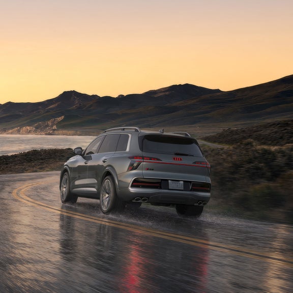 Three-quarter rear view of the Audi SQ9 accelerating on a wet road.