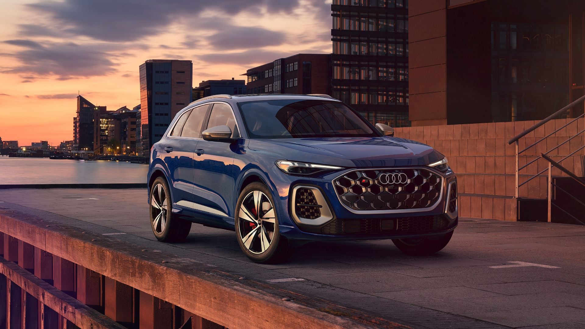 Dark Blue Audi SQ5 near a brick building at sunset