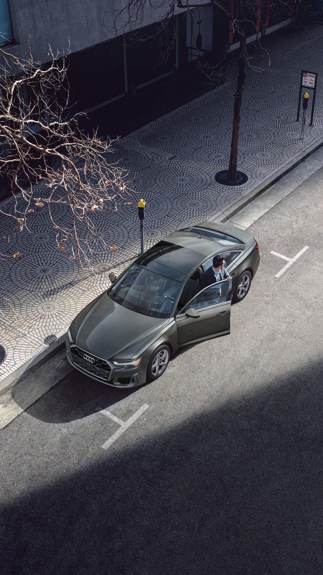 Aerial view of a person stepping out of the driver's side of the Audi A6 Sedan.