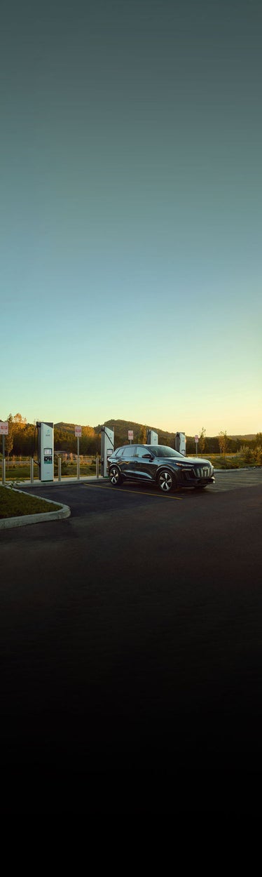 Three-quarter side view of an Audi e-tron vehicle charging at an Electrify America station.