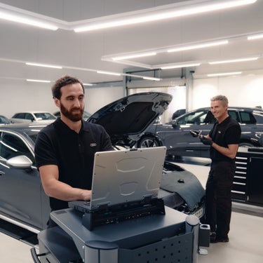 Deux techniciens Audi inspectent le bas d’un véhicule Audi.