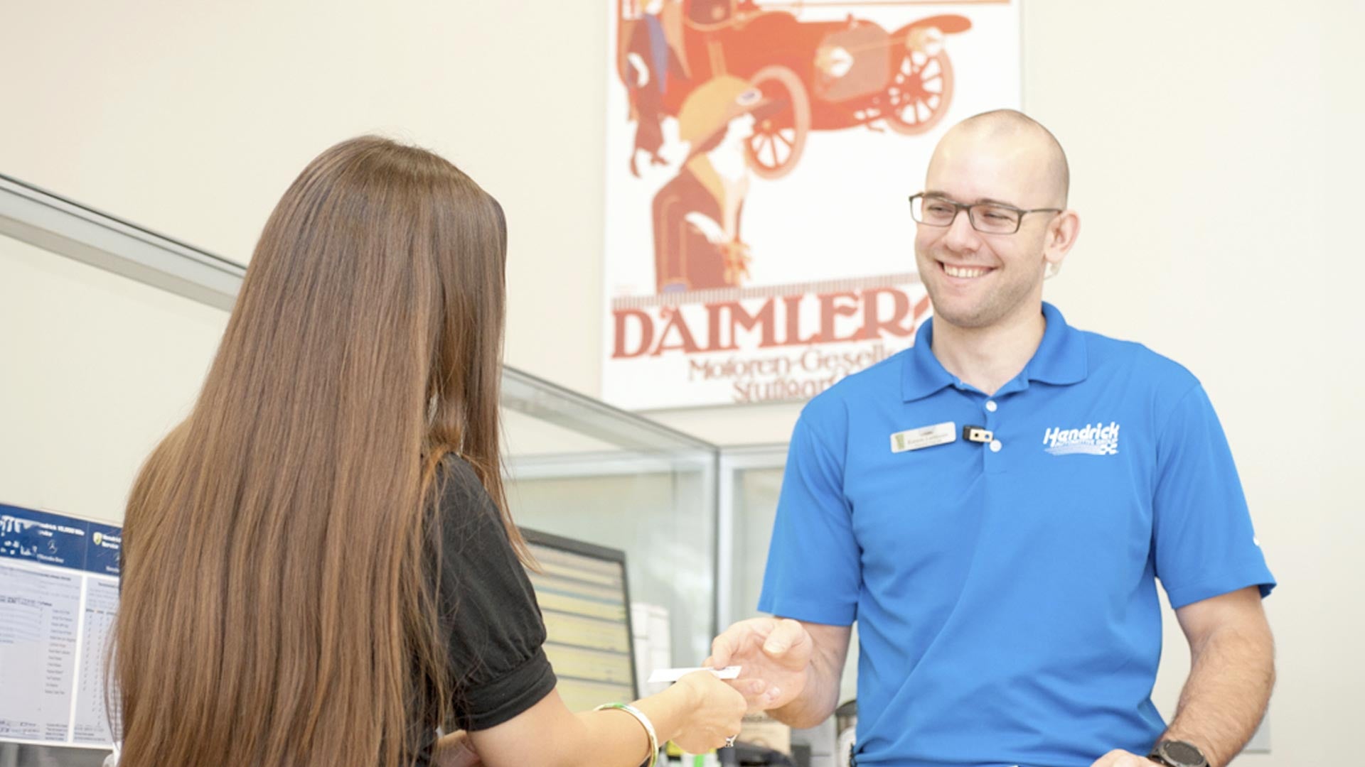 The sales specialist is handing the customer a key fob for an Audi vehicle. 