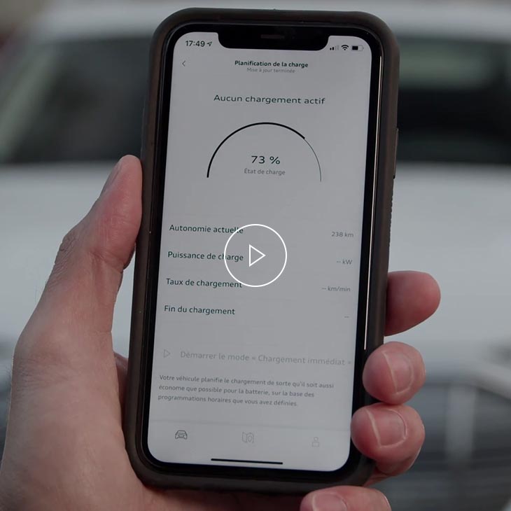 Photo d'une personne tenant un téléphone portable affichant l'interface de chargement de l'application myAudi.