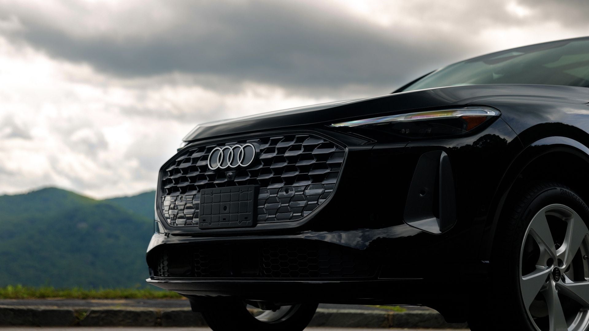 Close up of the front grille of a new Audi Q5 SUV with mountains in the background
