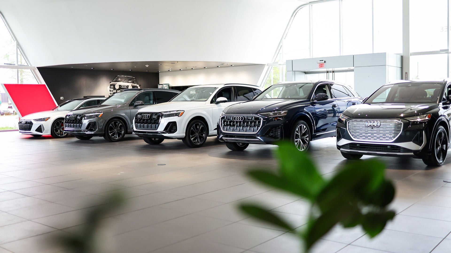 An Audi dealer explaining the features of an Audi vehicle steering wheel to a customer in the driver's seat.