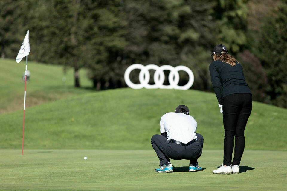 Two Golfers on the green, with an audi logo behind them