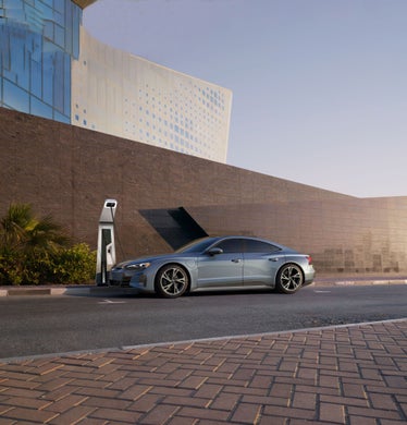 Side profile of an Audi e-tron GT parked at a charging station.