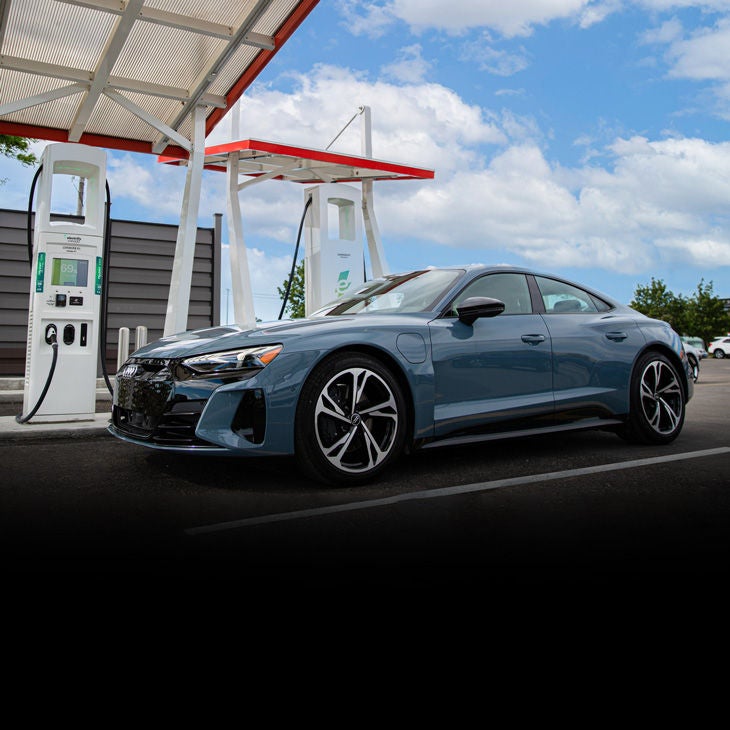 Close-up side profile of a blue Audi e-tron GT parked at a charging station.  