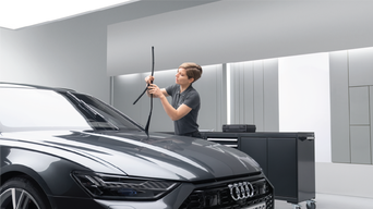Audi service technician changing wiper blades on a grey RS6
