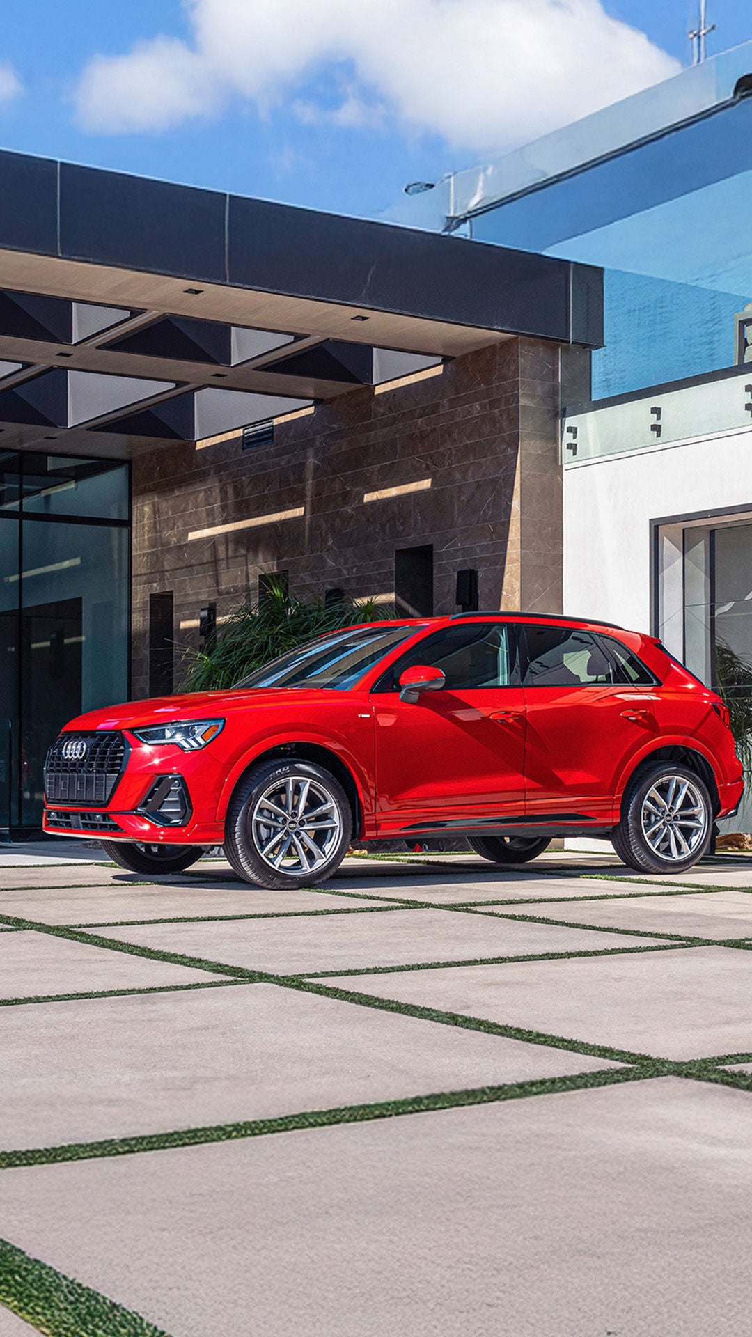 Side profile shot of the 2024 Audi Q3 parked in front of a modern house