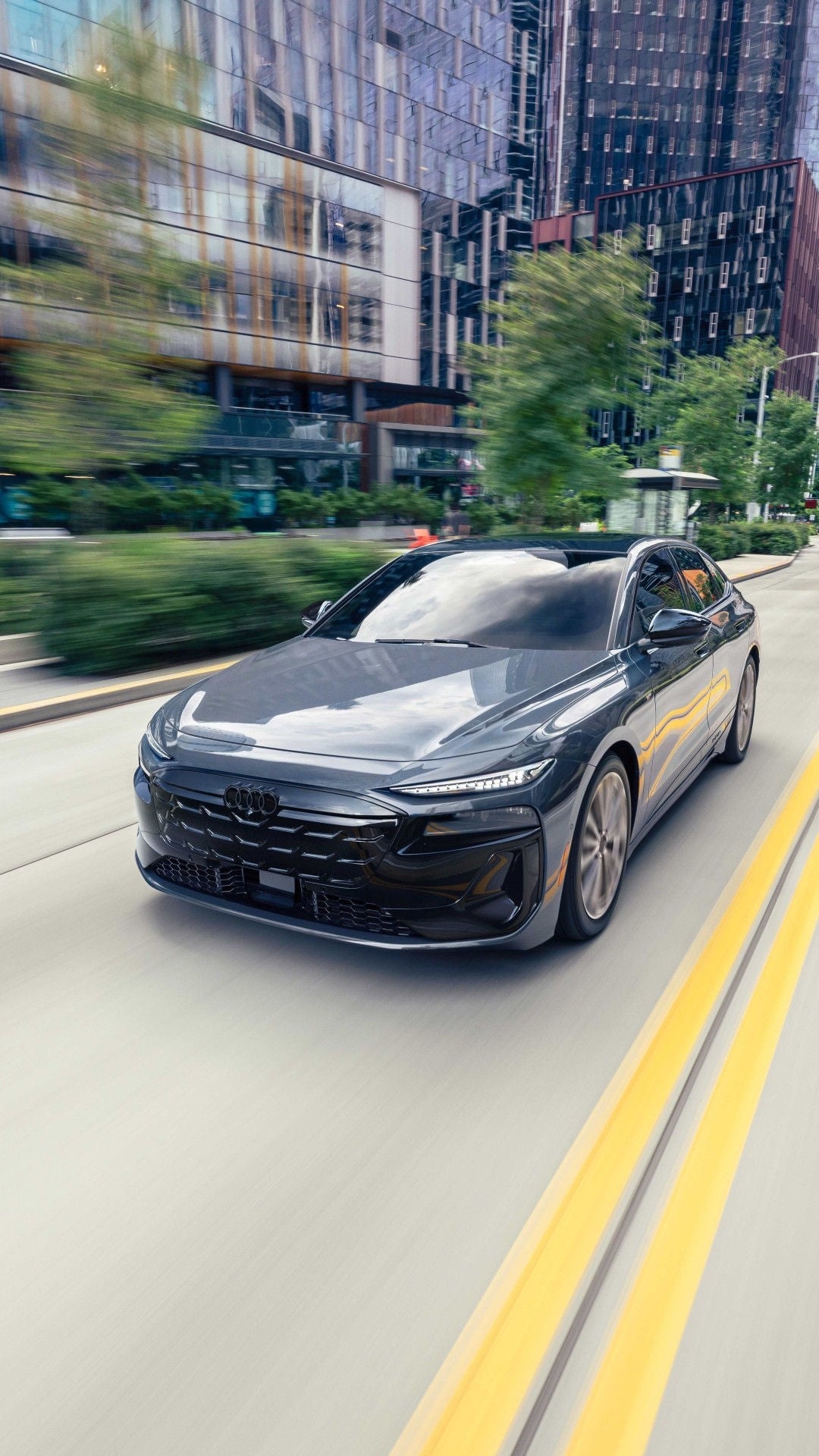 Three-quarter front-view of the Audi A6 sportback e-tron driving on a city street.
