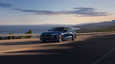 Three-quarter front view of the Audi S5 accelerating on a waterside road.