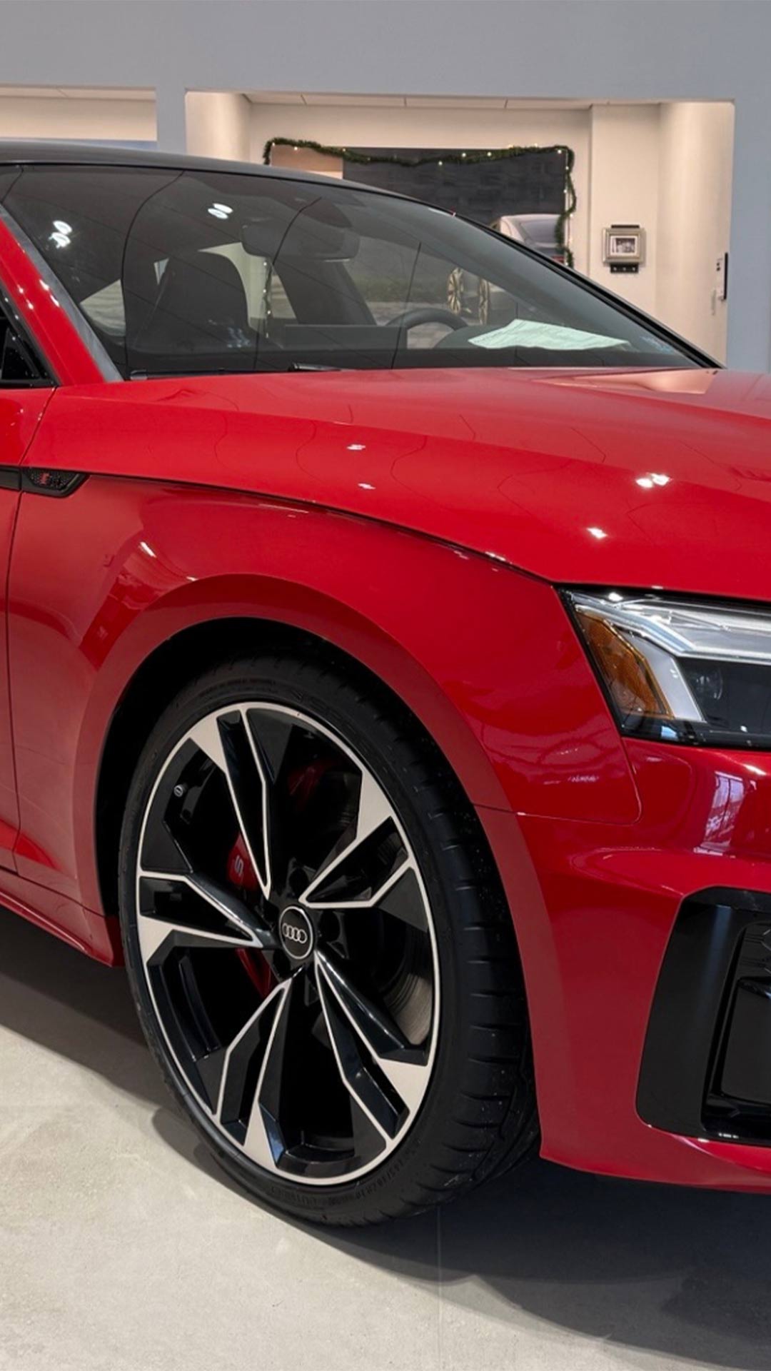 Right side profile of a red Audi in a dealership showroom