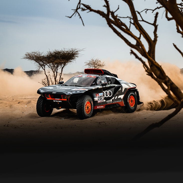 An Audi RS Q-etron kicking up dust on the road during the 2022 Dakar Rally.