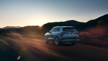 Three-quarter rear view of the Audi Q7 accelerating on a hillside road.