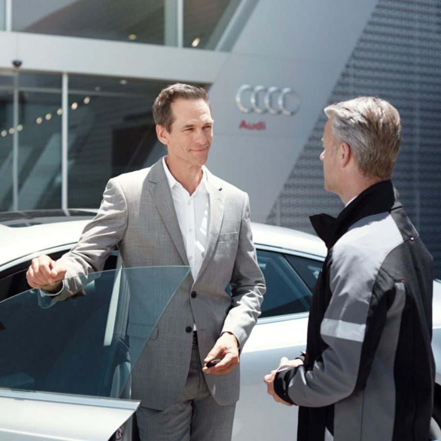 image of two people talking outside an Audi dealership