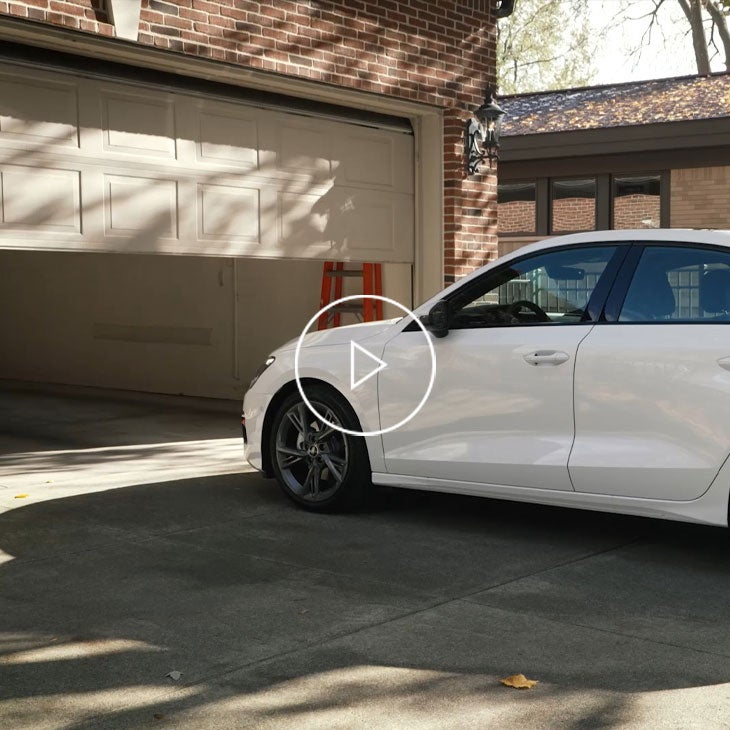 An Audi vehicle in front of an opening home garage door. 
