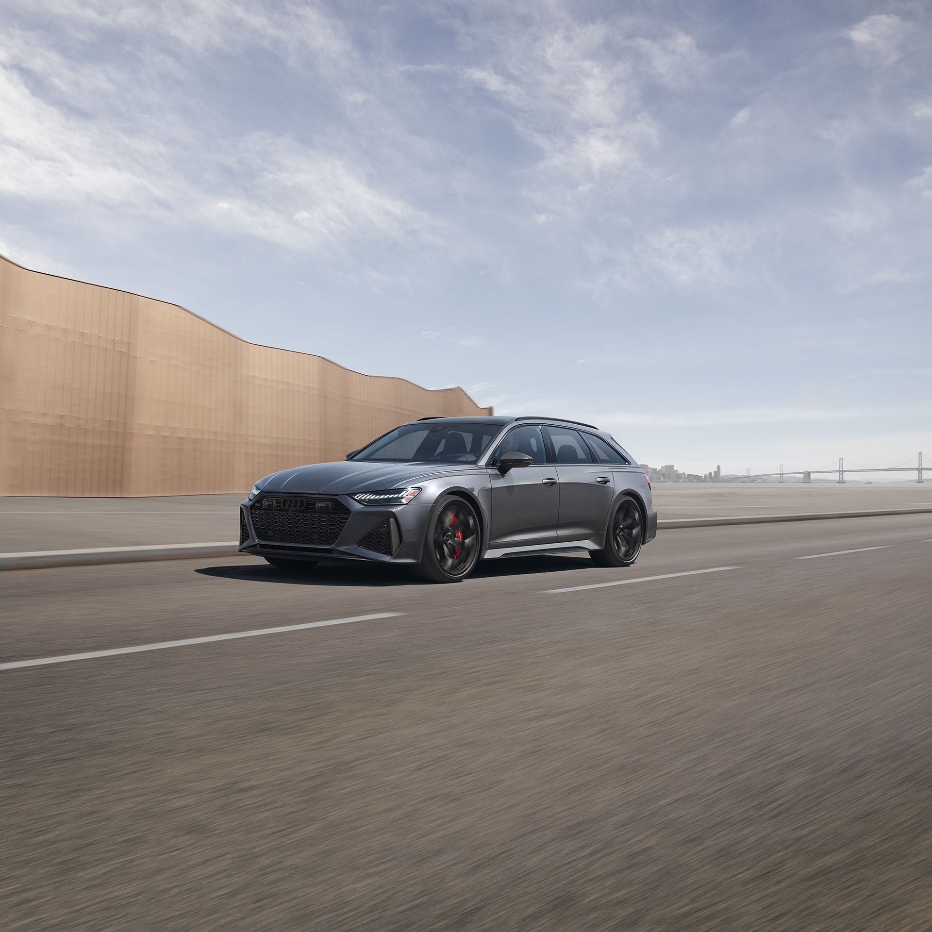 Vue arrière d’une Audi RS 6 Avant grise roulant sur une route côtière.