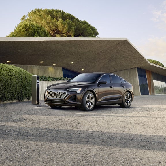 Side view of an Audi Q8 e-tron Sportback plugged into a charger.