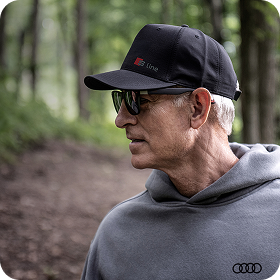 Side profile of a man wearing an Audi Collection hat and hoodie.