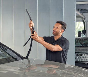 A technician replacing a windshield wiper blade