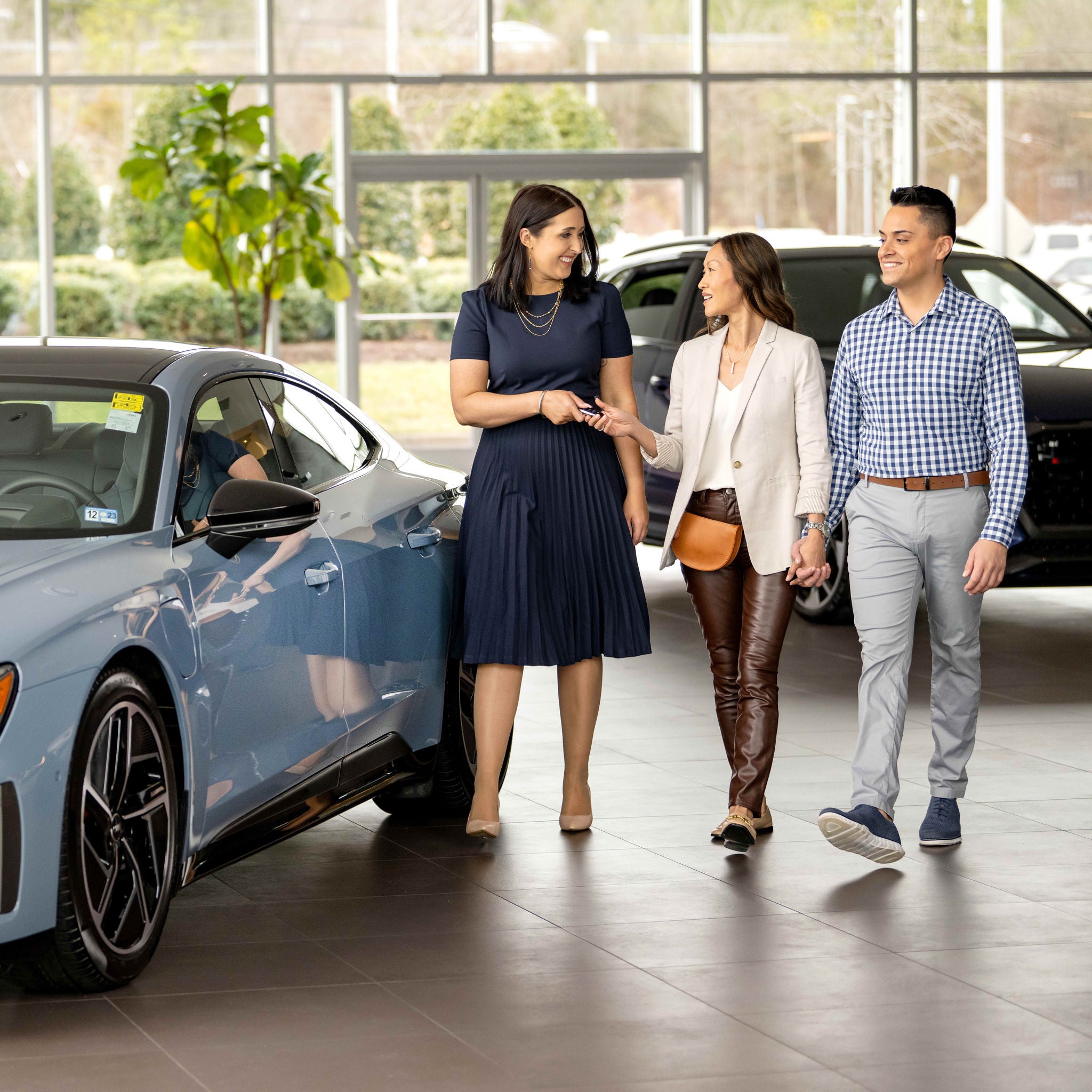 Three people walking through an Audi showroom, smiling.