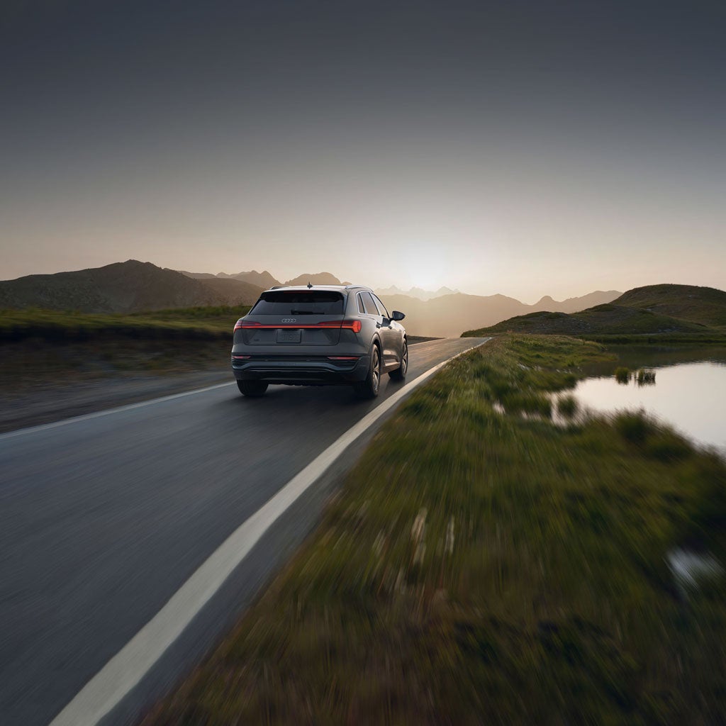 Vue arrière d’un Audi Q8 e-tron roulant sur une route de montagne.