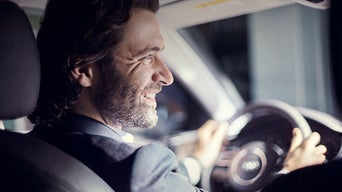 Over the shoulder view of a person driving an Audi vehicle.