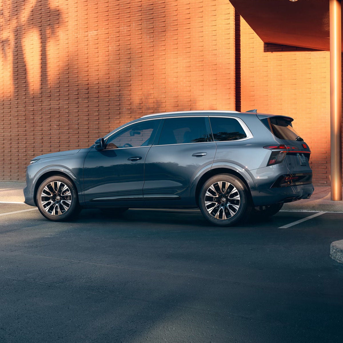 Three-quarter side view of the Audi Q7 parked by a modern building.