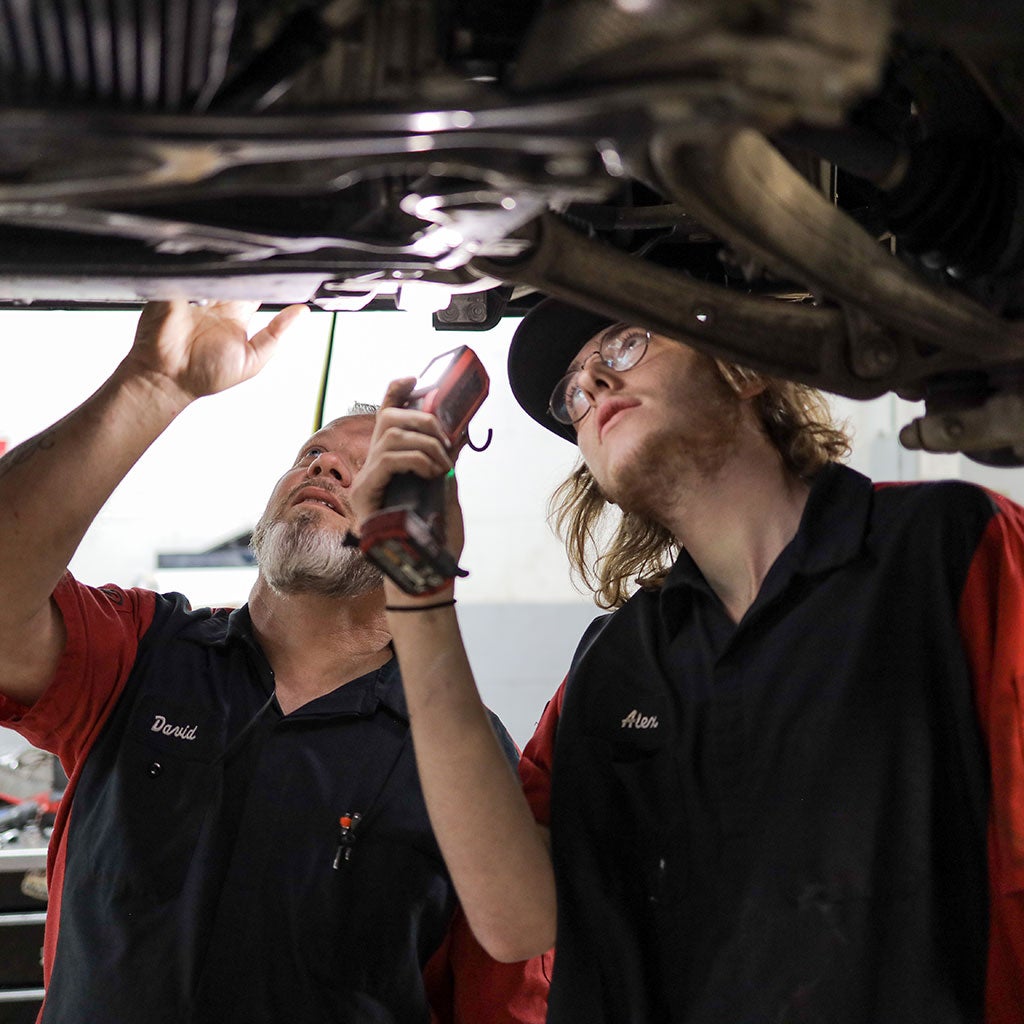 Two service technicians servicing a vehicle. 