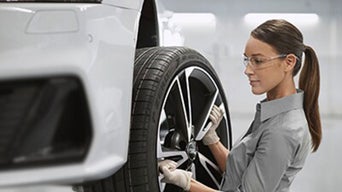Service technician mounting a tire onto an Audi vehicle.