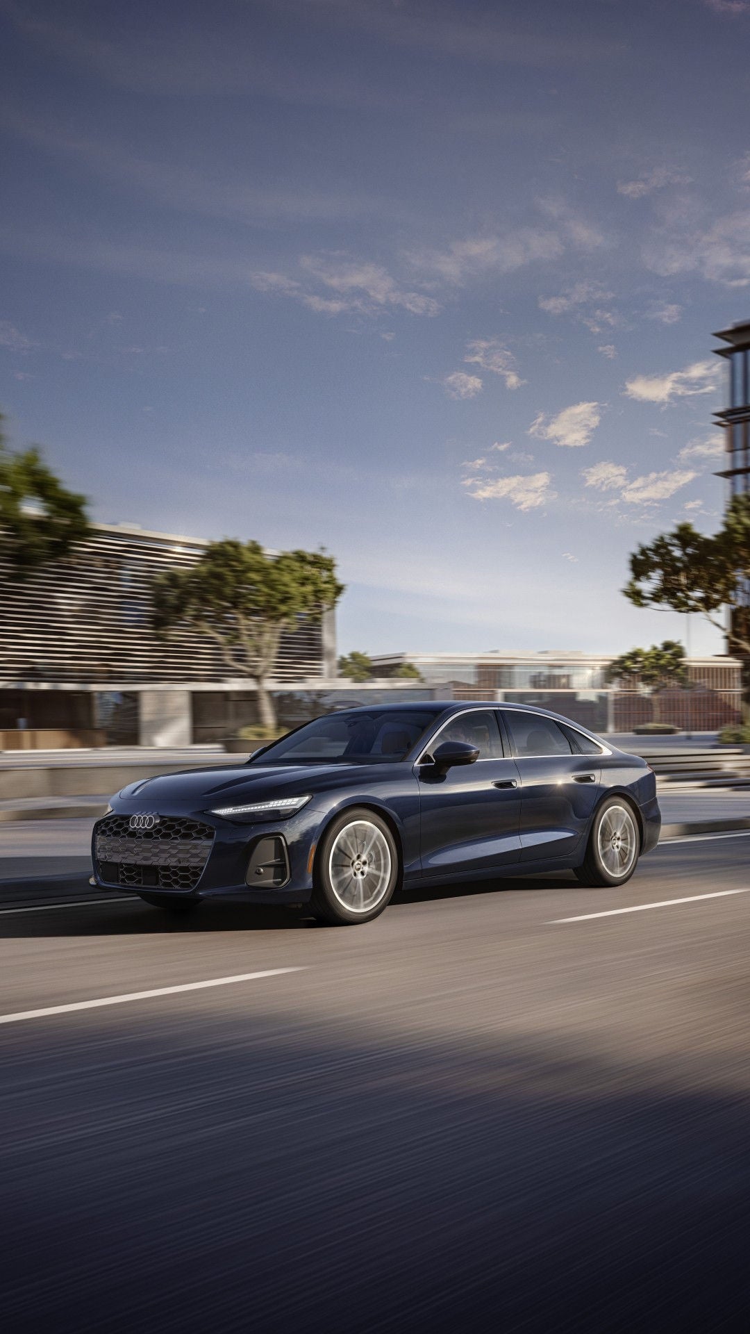 Three-quarter front view of the Audi A6 driving through the city.