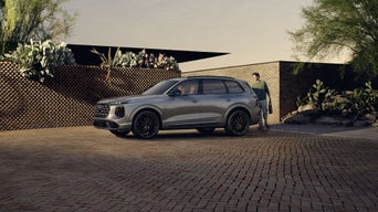 Three-quarter front-view of the Audi SQ7 parked on a driveway with a person opening up the trunk.