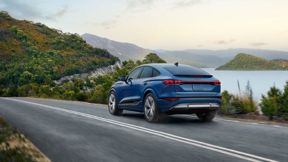 Side profile of an Audi e-tron GT driving on a futuristic suspension bridge.