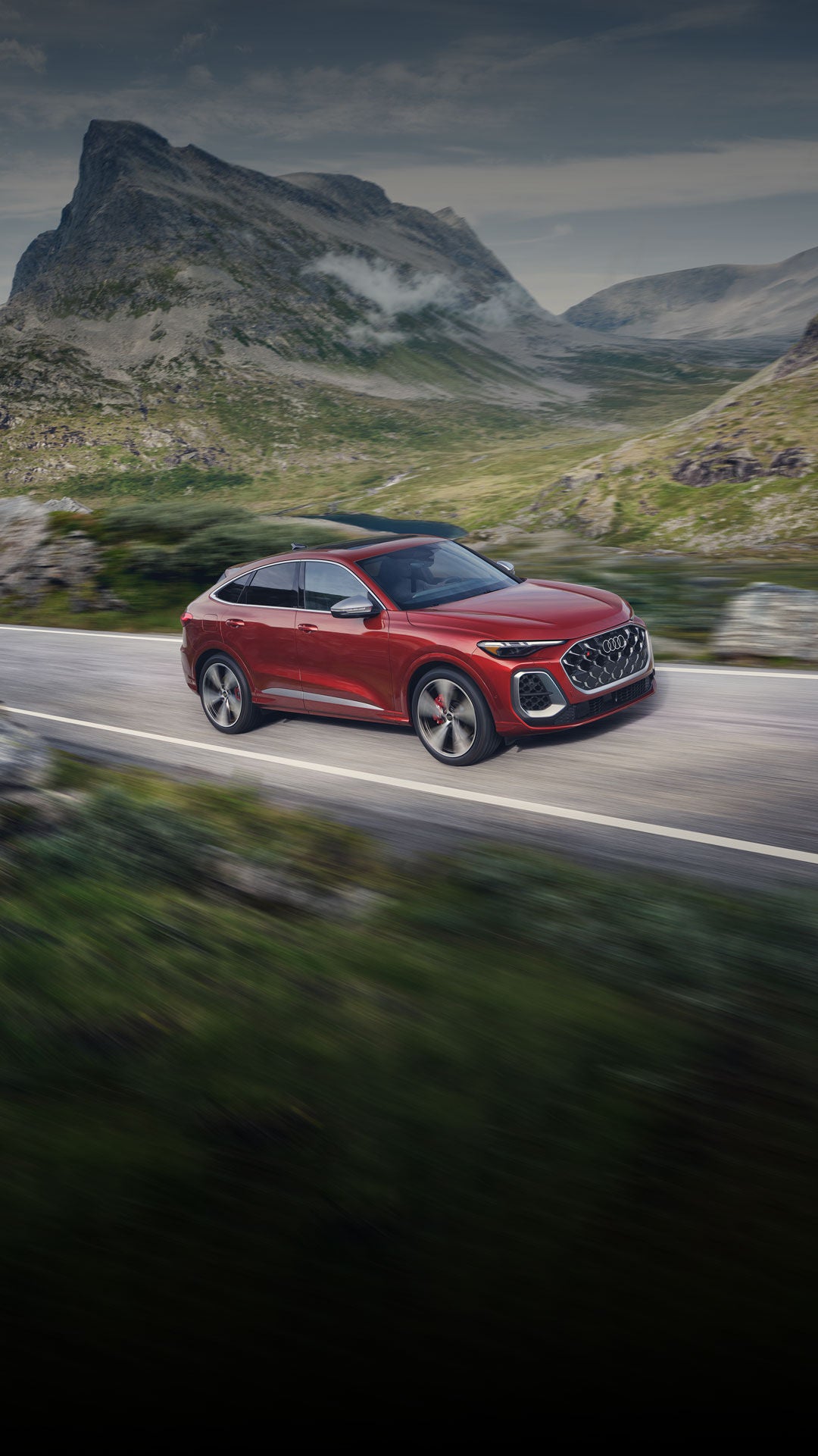 Three-quarter side view of the all-new Audi SQ5 Sportback accelerating on a mountain road.