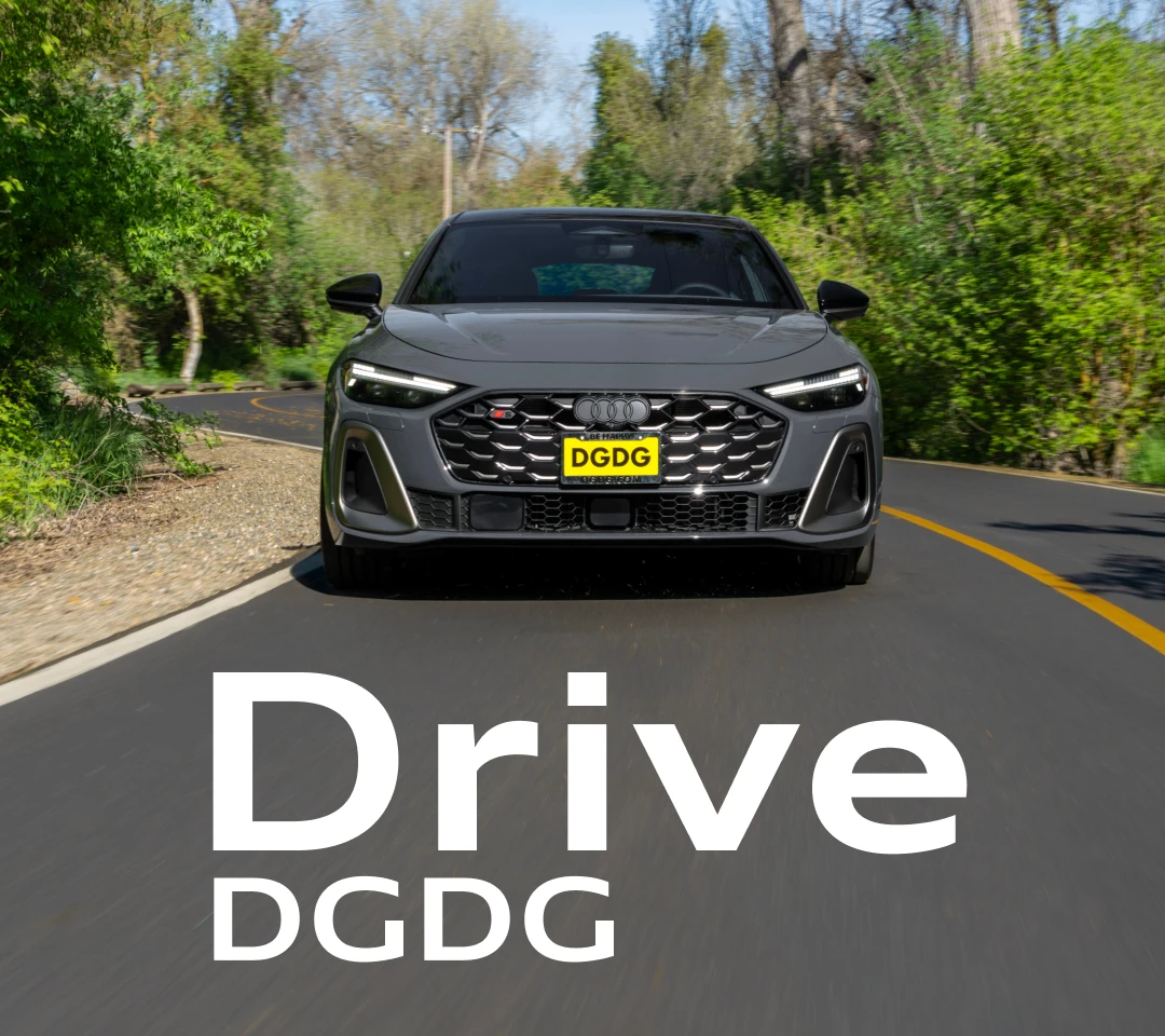 Front view of a grey Audi S5 sport sedan driving on a winding, tree-lined road.
