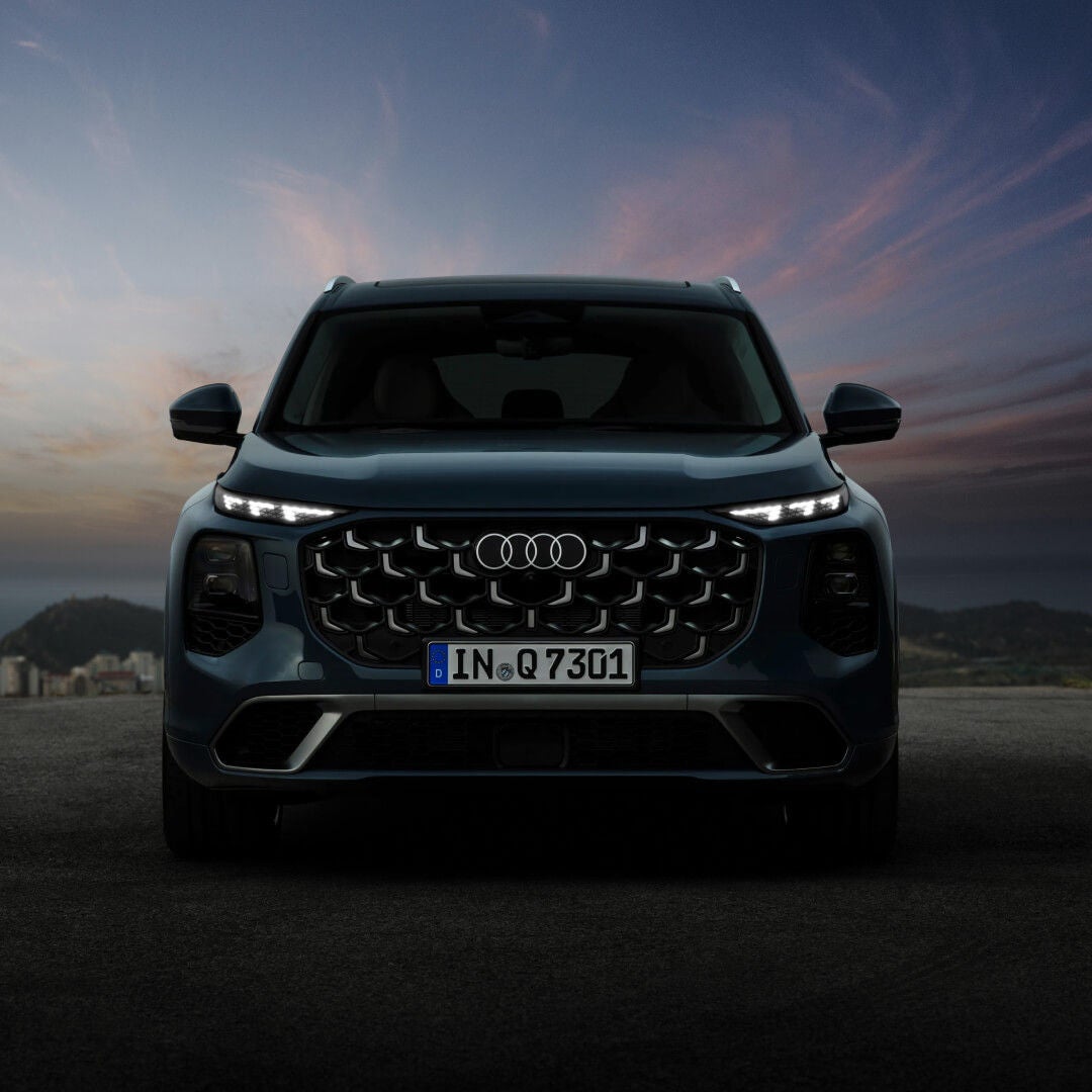 Direct front head-on view of an Audi Q7 in Blue Metallic parked on asphalt at twilight.