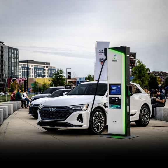 A white Audi Q8 e-tron hooked up to a charging station outside of Audi Field.