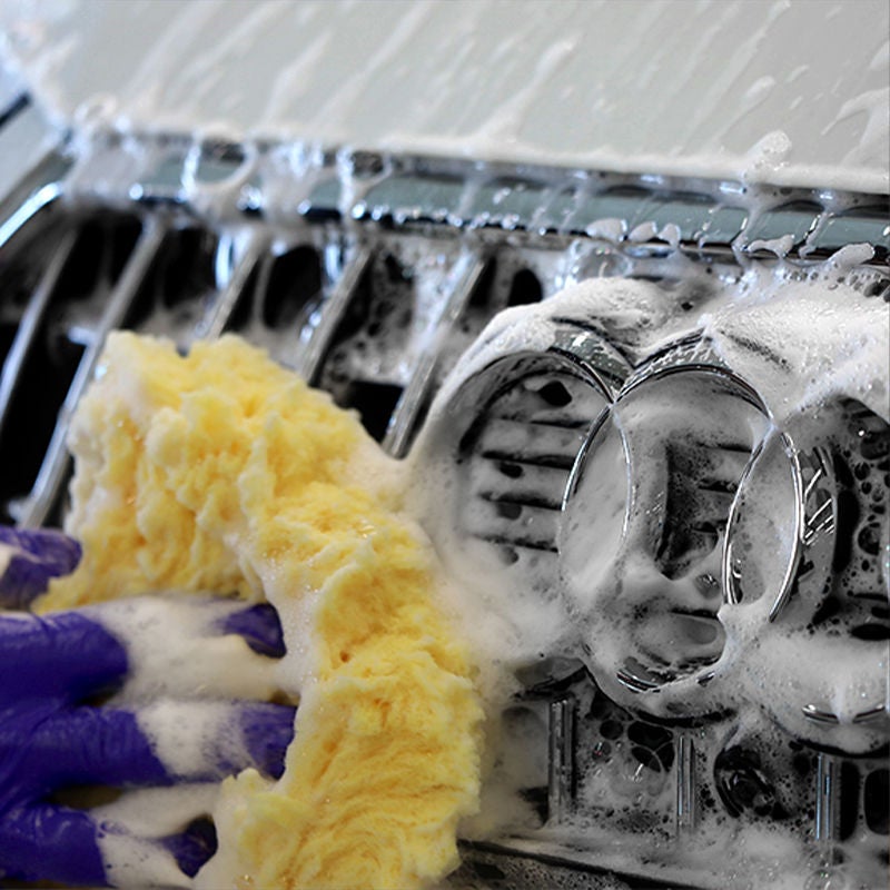 Image of a wash mitt and suds cleaning the Audi Rings 