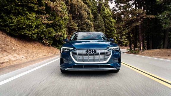 An Audi e-tron parked on a tiled road with grass in between each tile, near a handful of plants. 