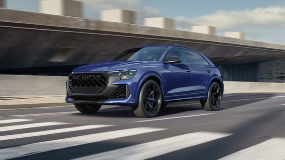  Front view of a blue Audi RS Q8 performance driving on an urban road.