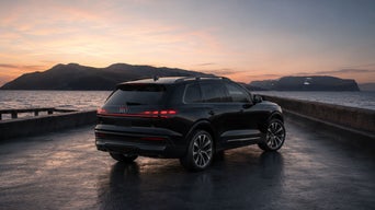 Three-quarter rear-view of the Audi Q9 parked by a waterfront.