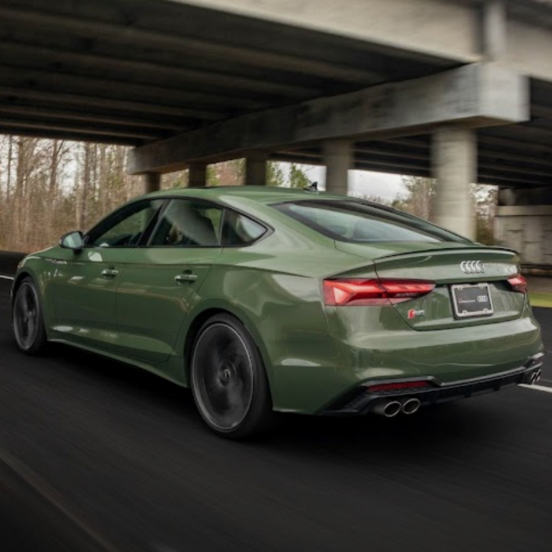 Rear view of a green Audi accelerating down the road.