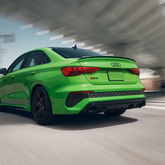 Rear view of a neon green Audi RS 3 in motion.